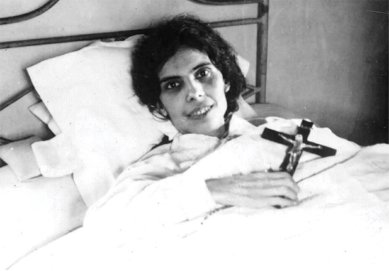imagem de Beata Alexandrina Maria da Costa segurando uma cruz e deitada em uma cama