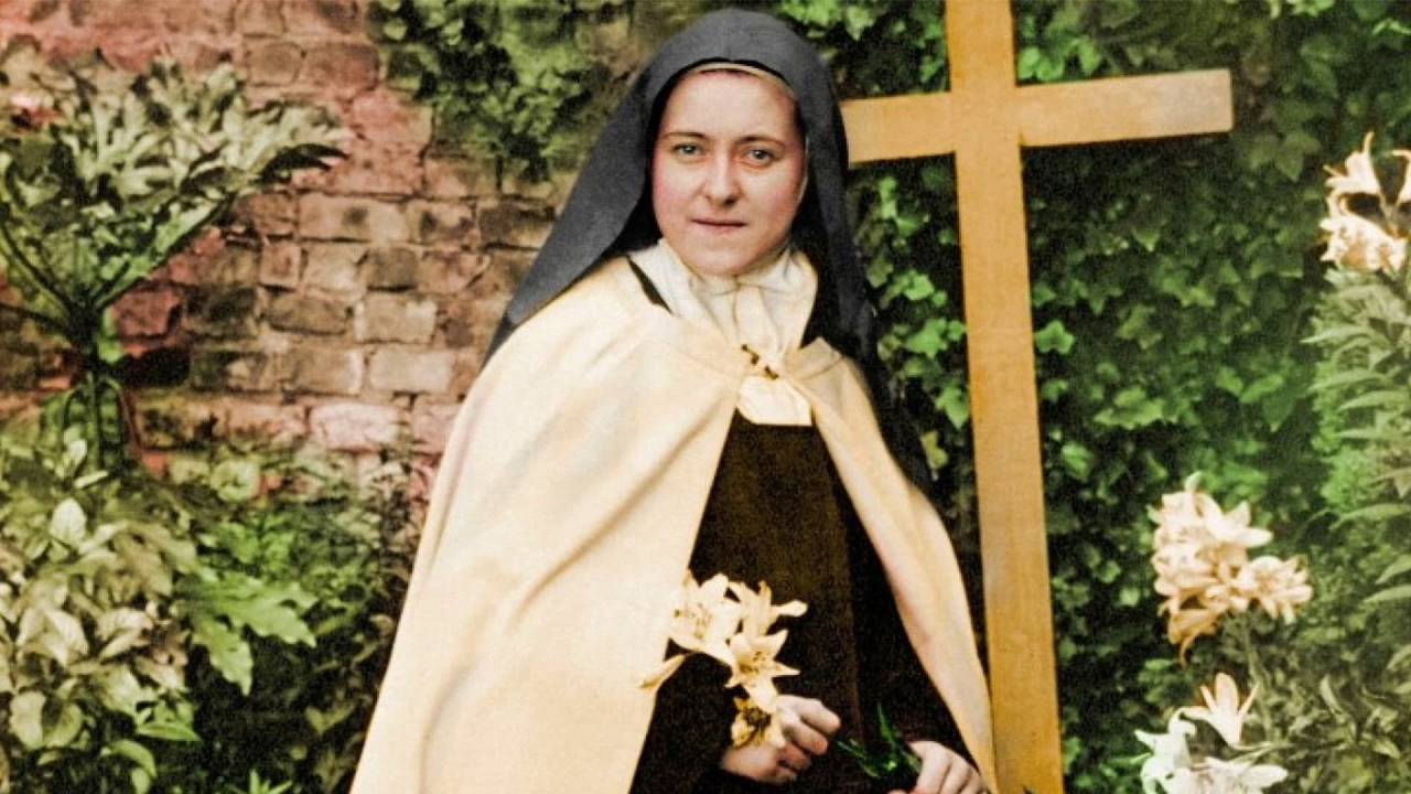 imagem de Santa Teresinha do Menino Jesus vestida com o hábito carmelita, marrom e branco, segurando lírios em suas mãos.